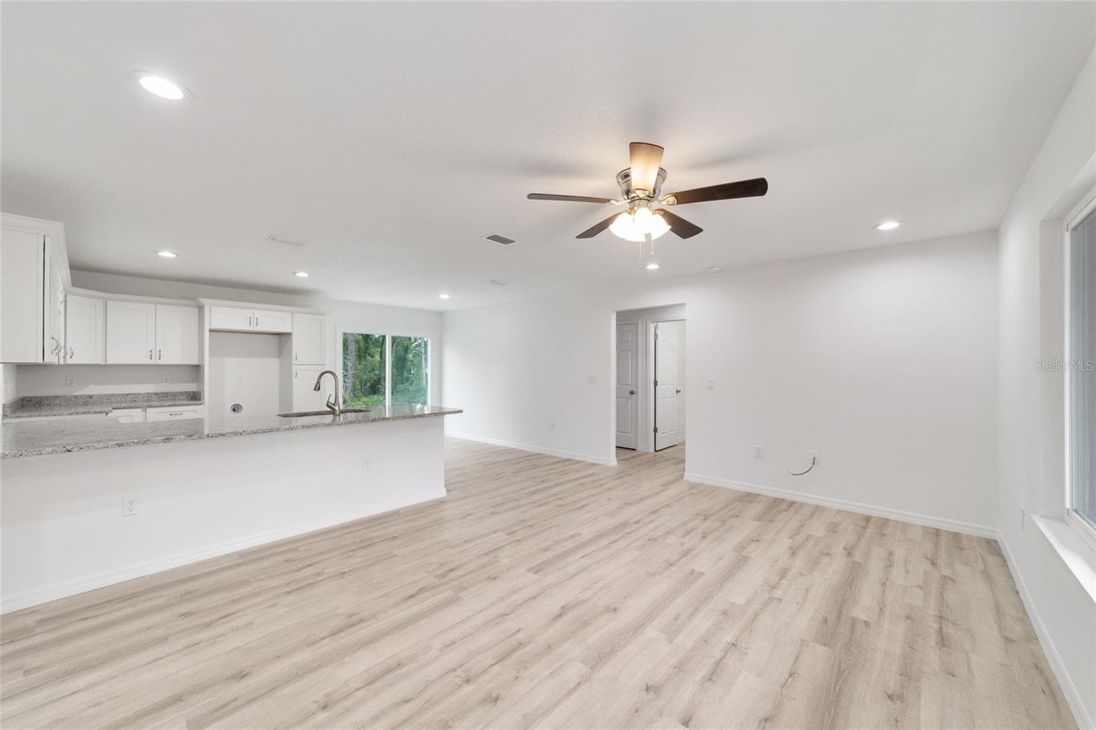 New-construction open kitchen and great room with granite island in Central Florida by CFL Home Builders